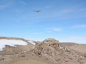 Markus Landgraf a Shannon Hinsa zkoumají skálu Hellas Rock zatímco na obloze letí Twin Otter.